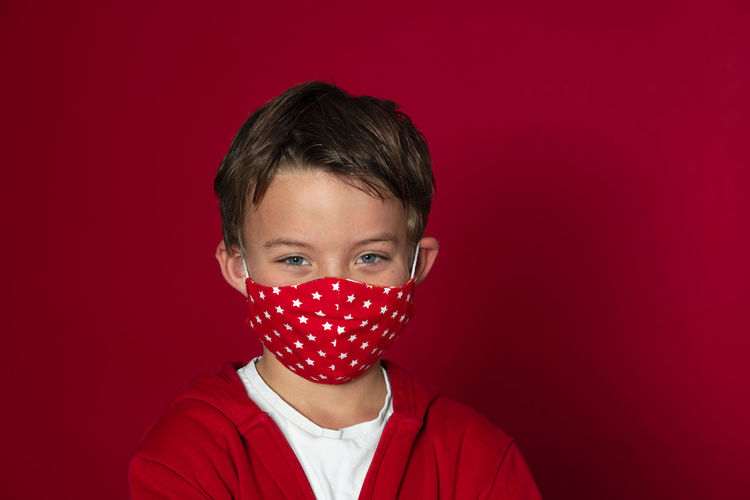Close-up portrait of boy against red background