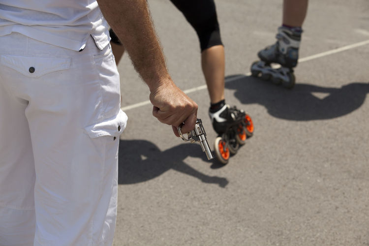 Midsection of man holding gun by inline skaters during competition