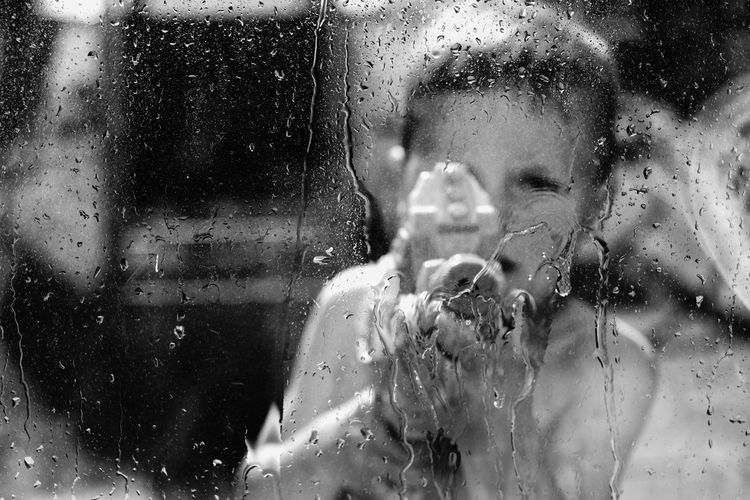 Close-up of boy spraying water on glass window