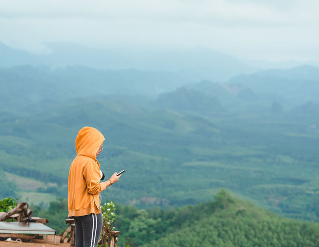 Woman tourist are using phone to take pictures of beautiful mountain scenery