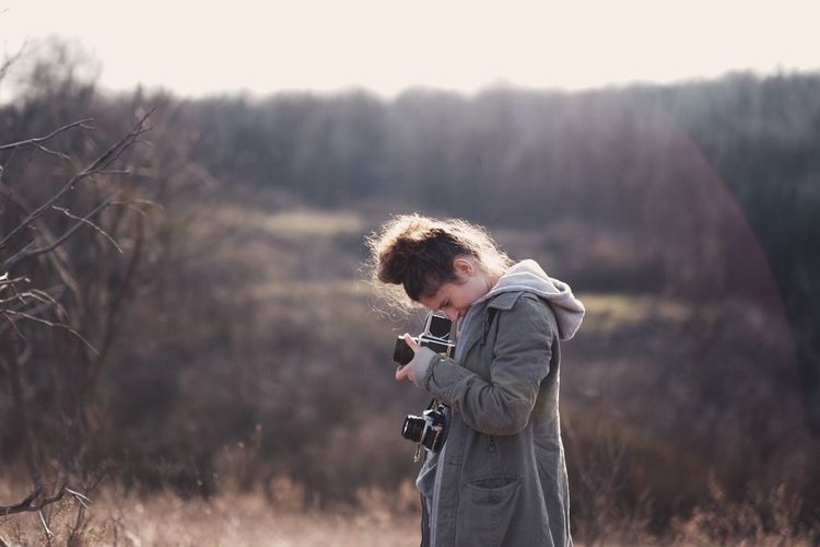 Side view of woman photographing through camera