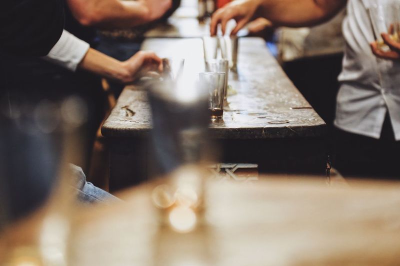 People sitting around a  table in a bar at night only showing the hands and empty glasses 