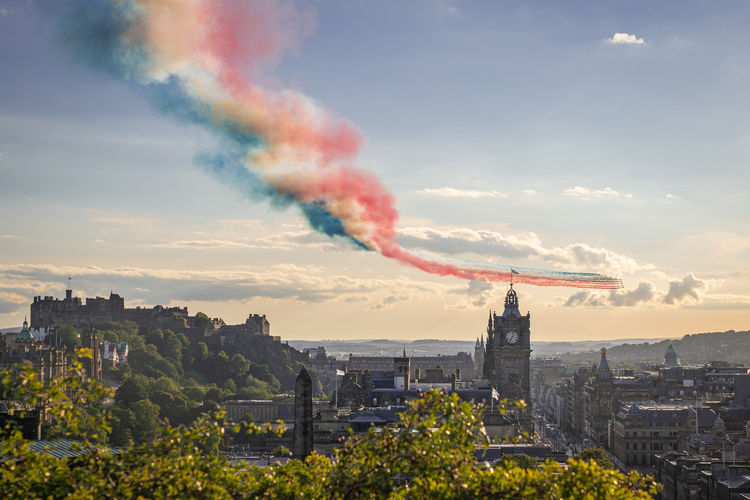 Red arrows flypast over edinburgh city in scotland at sunset.