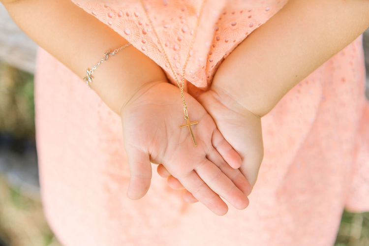 A cross on a chain on the palms of the girl who was baptized