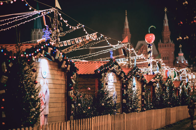 Illuminated market stalls decorated during christmas against church at night