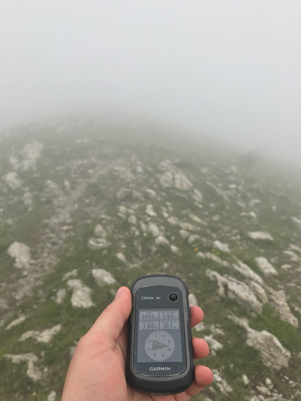 MIDSECTION OF PERSON HOLDING MOBILE PHONE AGAINST MOUNTAINS
