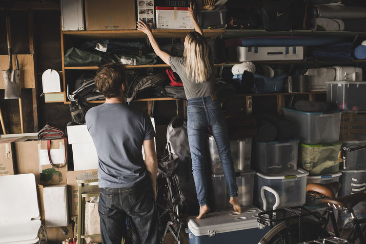 Man looking at woman while she adjusting boxes at home