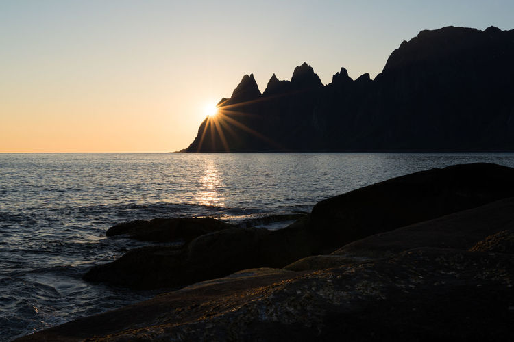 Midnight sun hitting scenic cliffs of tungeneset on senja in northern norway at a warm summer night