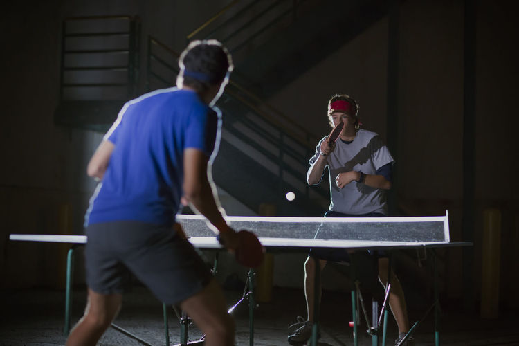 Men playing table tennis against illuminated building