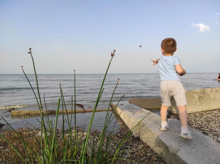 Boy throws stones into the sea