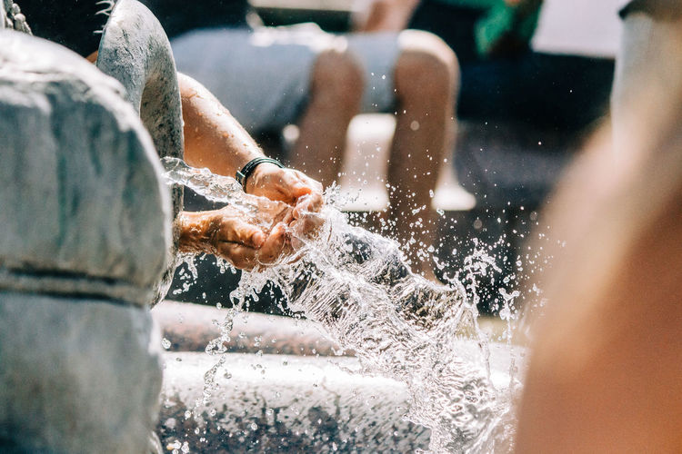 Cropped image of person washing hands in fountain