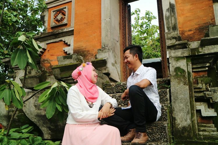 Low angle view of smiling couple looking at each other while sitting on steps