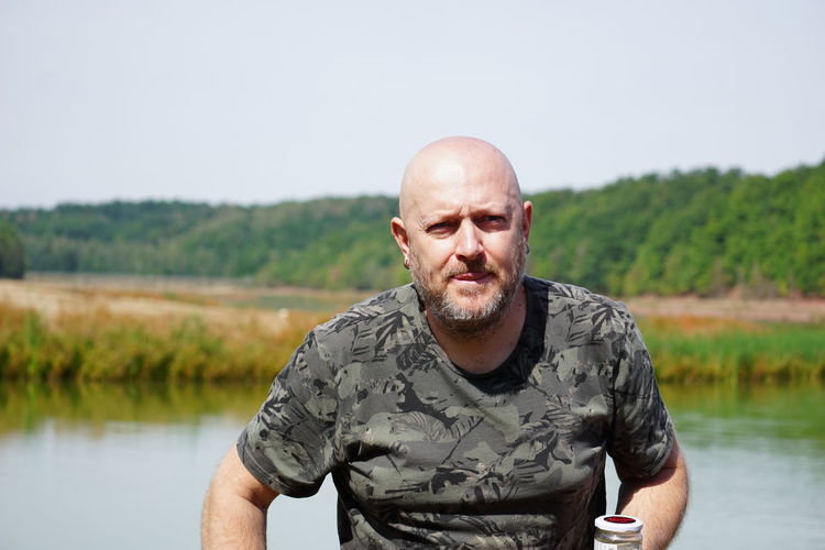 Portrait of man standing against lake