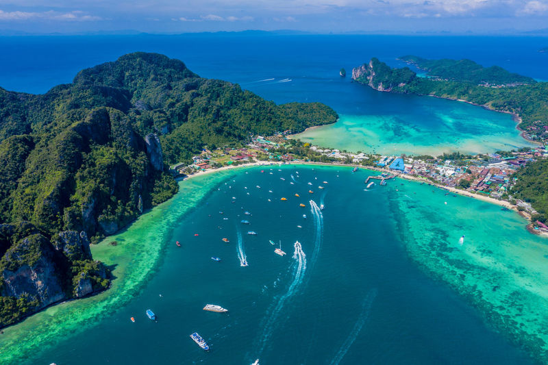 Blue clear water with boats. green tropical island phi phi, palm trees grow. shooting  from the air