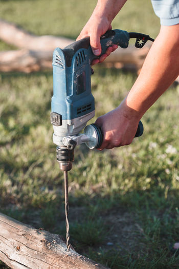 Close-up of carpenter drilling on wood