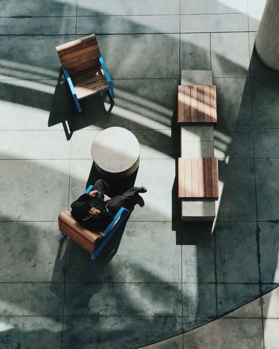 High angle view of man sitting outdoors on paved terrace