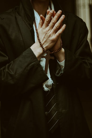 Midsection of man holding rosary beads