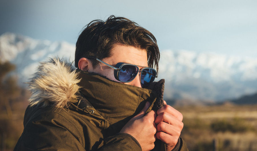 Portrait of man wearing sunglasses against sky during winter