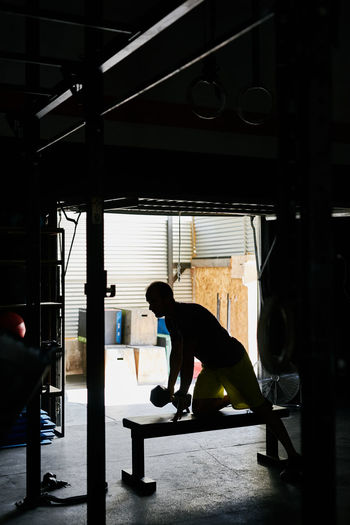 Young man working out in a indoors garage gym with dumbbell
