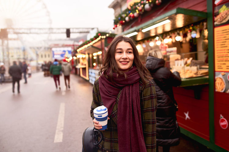 Pretty woman holding reusable coffee cup at the christmas market