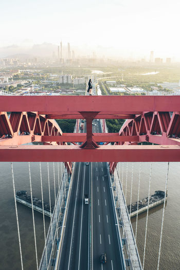 Woman standing on cable-stayed bridge over river in city