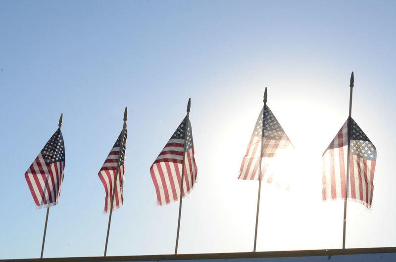 Low angle view of american flags waving against clear sky