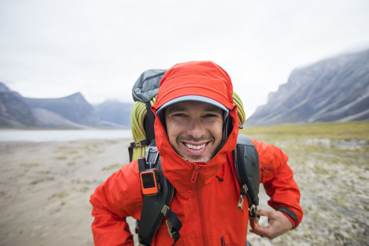 Portrait of smiling man standing on mountain against sky