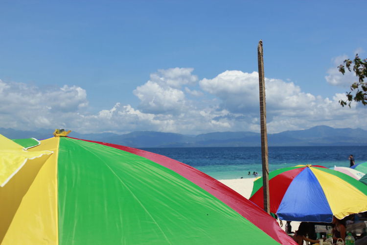 Multi colored umbrellas on beach against blue sky
