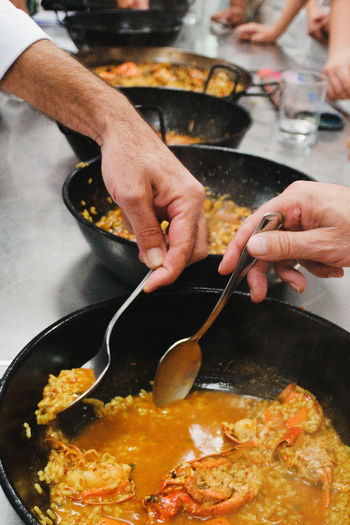 Close-up of men hands tasting food in cooking pans. 
