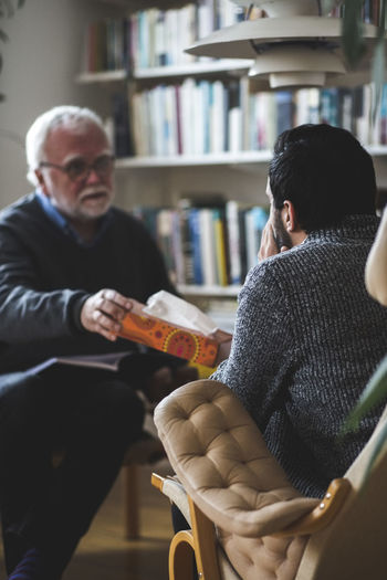Therapist giving tissue box to male patient at home office