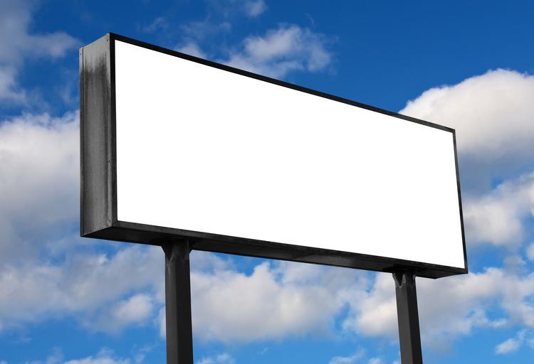 Low angle view of blank billboard against cloudy sky