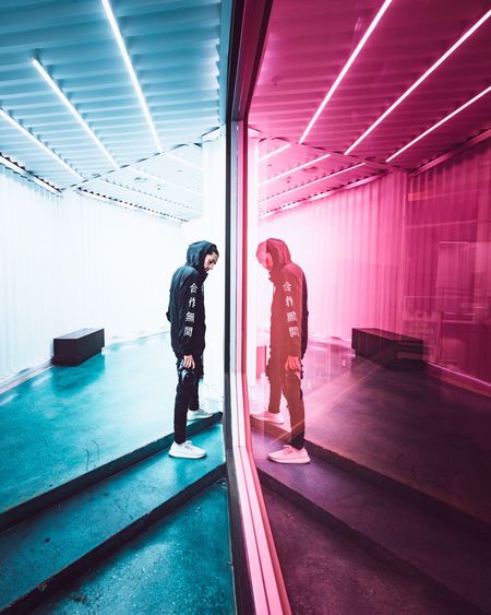 Full length of man and woman standing against illuminated wall