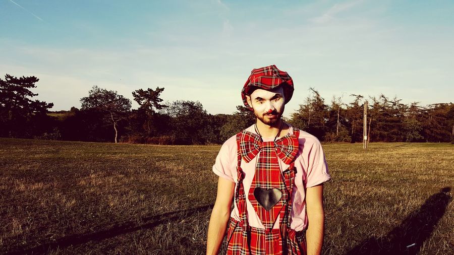 Portrait of man wearing clown costume while standing on field