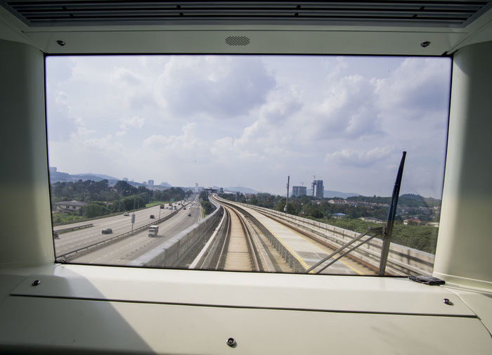 Railroad tracks against sky seen through train windshield