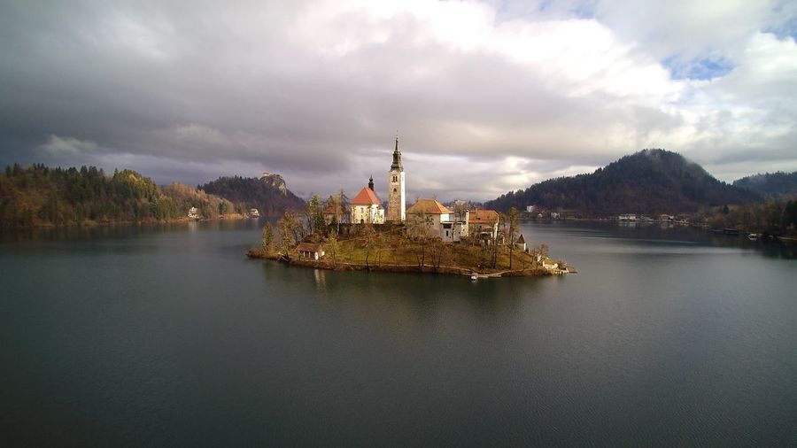 Scenic view of lake bled against cloudy sky