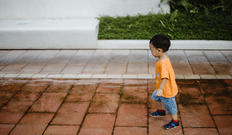 Side view of boy standing on footpath