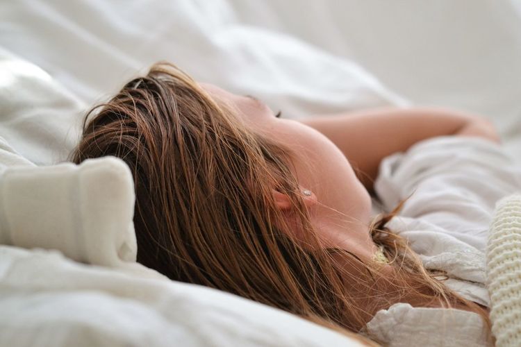 Close-up of woman sleeping in bed at home