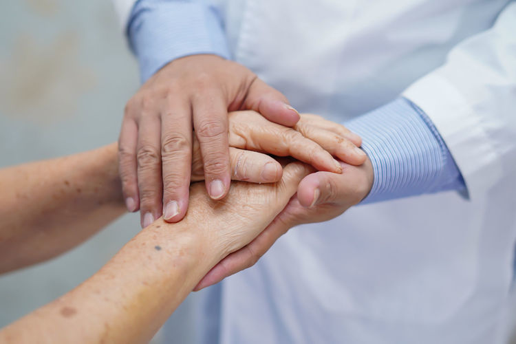 Midsection of doctor holding patient hands