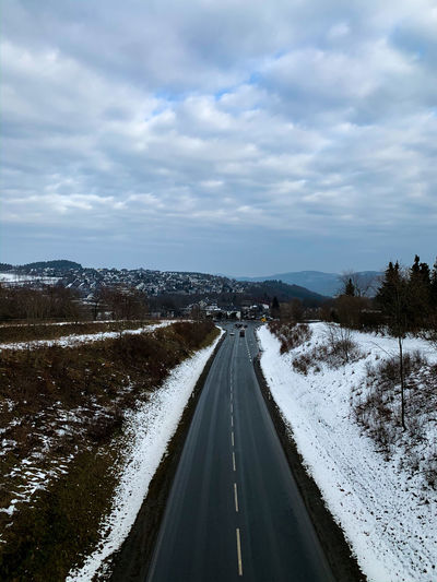Snow covered road against sky during winter