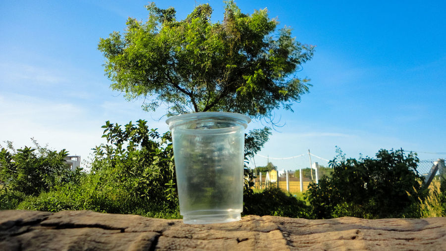 Drinking glass on table against sky