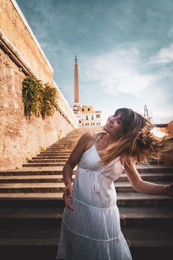 Full length of woman standing by building against sky