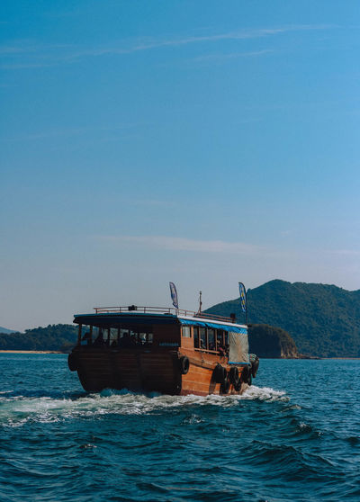 Ship sailing on sea against clear blue sky
