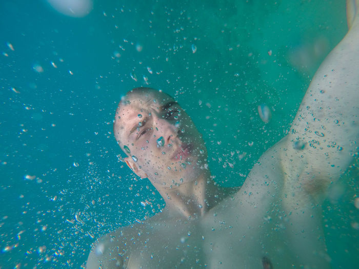 Close-up of shirtless man swimming in sea