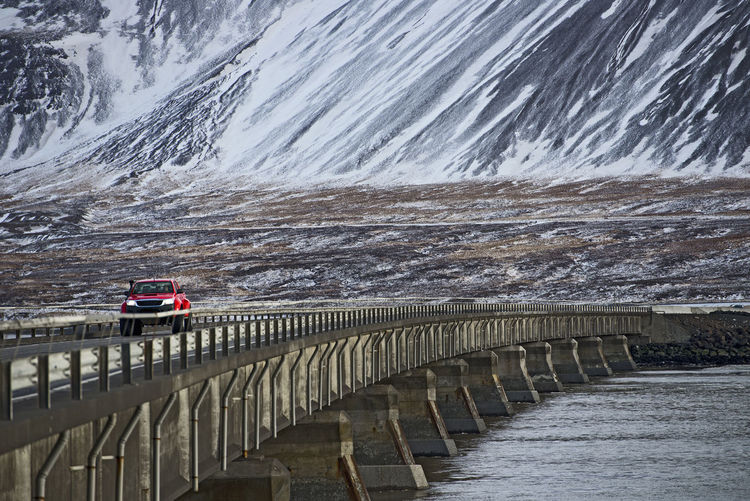Red pick up truck driving over bridge in iceland