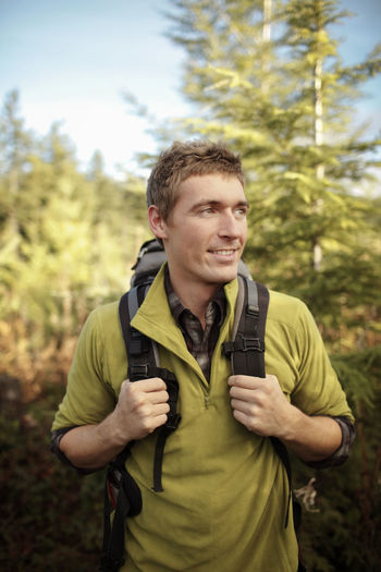 Male hiker looking away while standing in forest