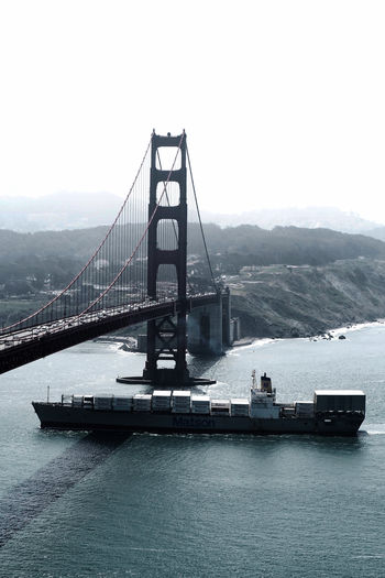 High angle view of container ship sailing at bay over golden gate bridge