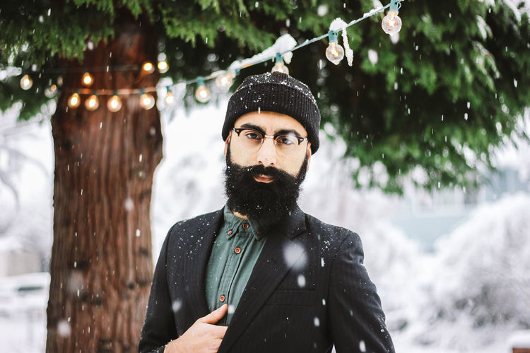 Portrait of young man standing outdoors during snowfall