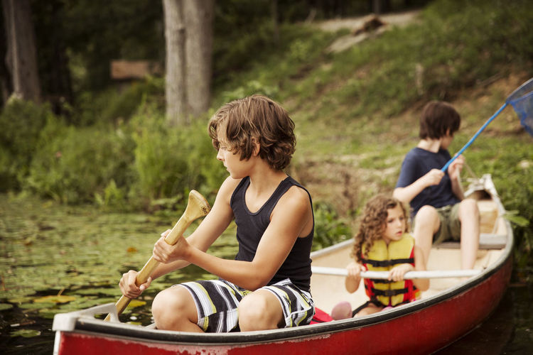 Children oaring while sitting in canoe