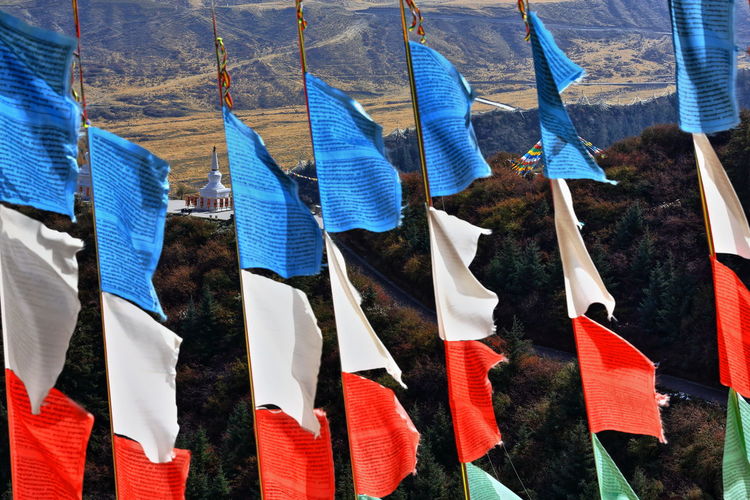 Multi colored flags hanging against landscape