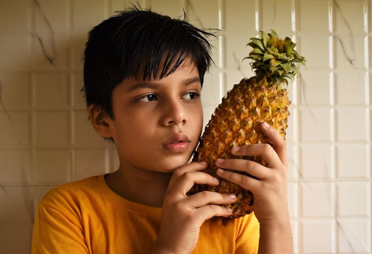 Portrait of boy holding pineapple